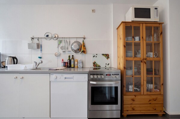 A kitchen with a microwave, oven, and various utensils on the wall.