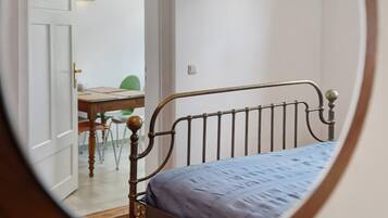 Ein Schlafzimmer mit einem Metallbettgestell, einem Holztisch und einem Stuhl im Hintergrund.