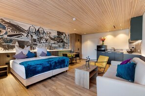 Una habitación de hotel moderna con cama, sofá, mesa de centro y un mural en la pared.