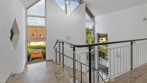 Un interior moderno con una escalera, ventanas amplias y vistas al exterior.