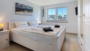 A bedroom with a bed, bedside tables, a window, and a painting on the wall. - Holiday Home 'Ferienhaus Strandperle' with Private Terrace, Private Garden and Wi-Fi (Ostseebad Zingst)