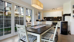 A modern kitchen with white cabinets, a central island, and a wood-burning stove. - Holiday Home 'Ferienhaus Strandperle' with Private Terrace, Private Garden and Wi-Fi (Ostseebad Zingst)