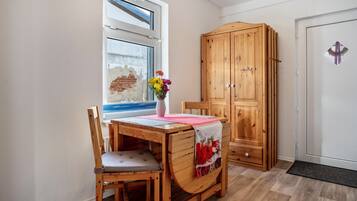 Una mesa de comedor de madera con una silla, un mueble de madera y una ventana que da a un muro de ladrillo.