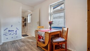 A dining area with a wooden table, a chair, a vase with flowers, and a wall with a pet paw print decoration. - Pet-Friendly Apartment in the Lake District (Fünfseen Ot Petersdorf)
