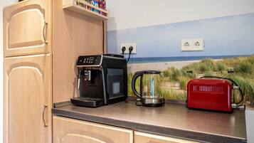 A kitchen with a coffee maker, a red toaster, and a wall outlet.