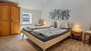 Un dormitorio con una cama de madera, una mesita de noche, un armario, una ventana con vistas y un mural en la pared.