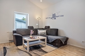 A living room with a sofa, a coffee table, a floor lamp, and a wall decoration.