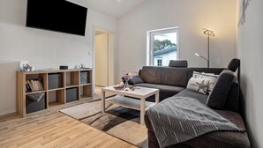 Una sala de estar moderna con una televisión de pantalla plana, un sofá, una mesa de centro y una estantería.