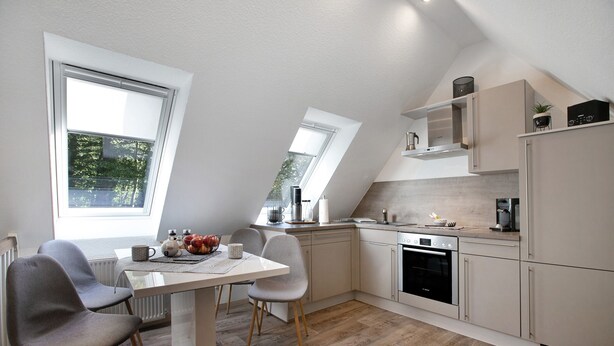 A modern kitchen with a dining area, large windows, and a sloped ceiling. - Apartment 'Kleine Nock' with Balcony and Wi-Fi (Burg (Dithmarschen))