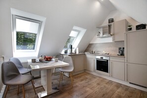 Eine moderne Küche mit Essbereich, großen Fenstern und einer schrägen Decke.