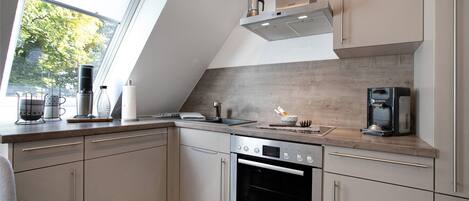 A modern kitchen with a Bosch oven, a coffee maker, and a window with a view of trees.
