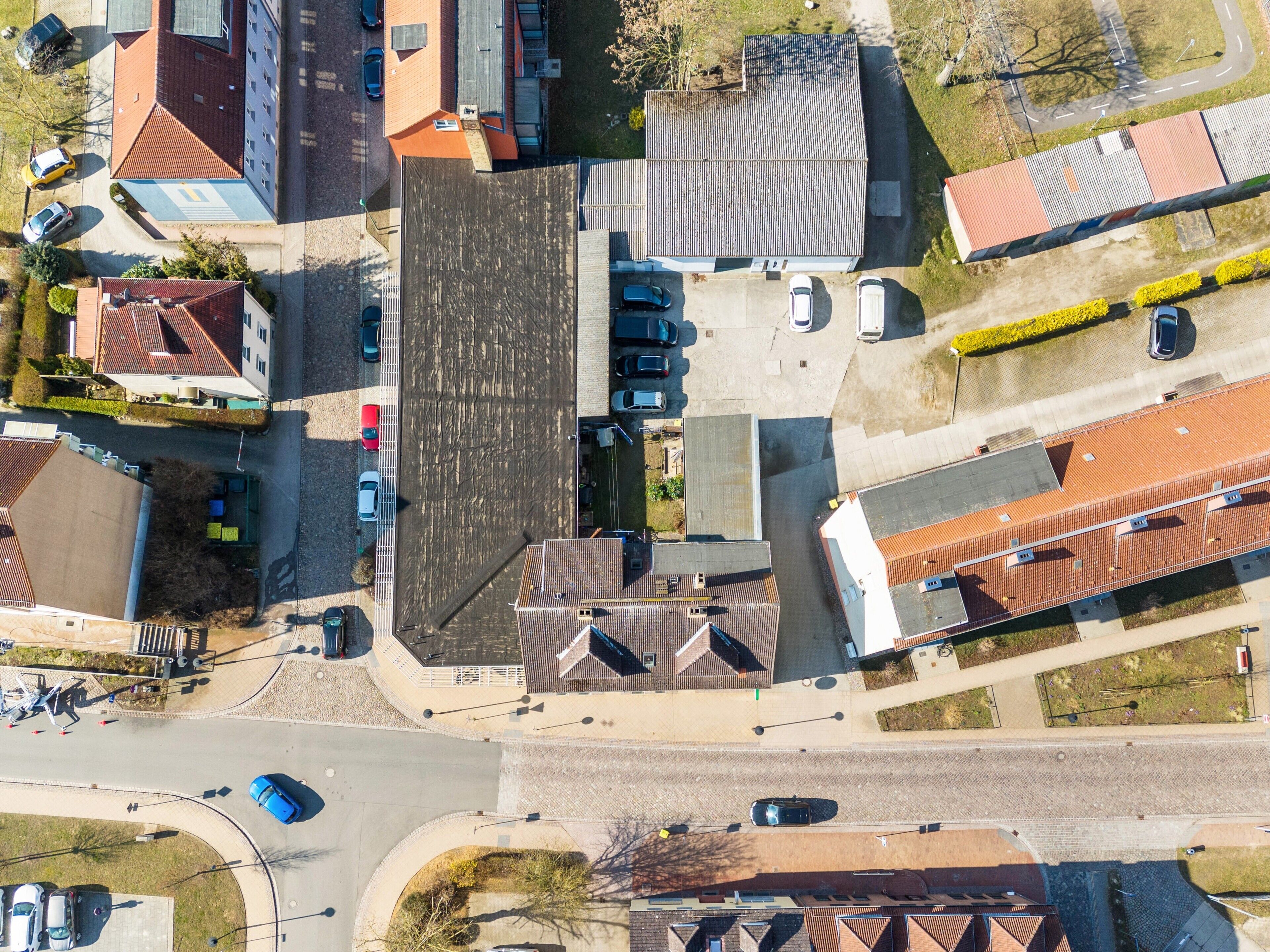 Una vista aerea di una zona residenziale con diversi edifici, strade e auto parcheggiate.