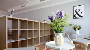 A room with a white round table, a bookshelf, and two chairs.