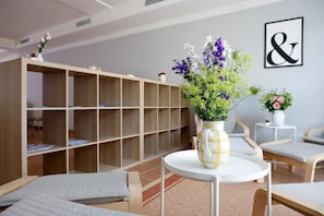 Une pièce avec une table ronde blanche, une bibliothèque et deux chaises.