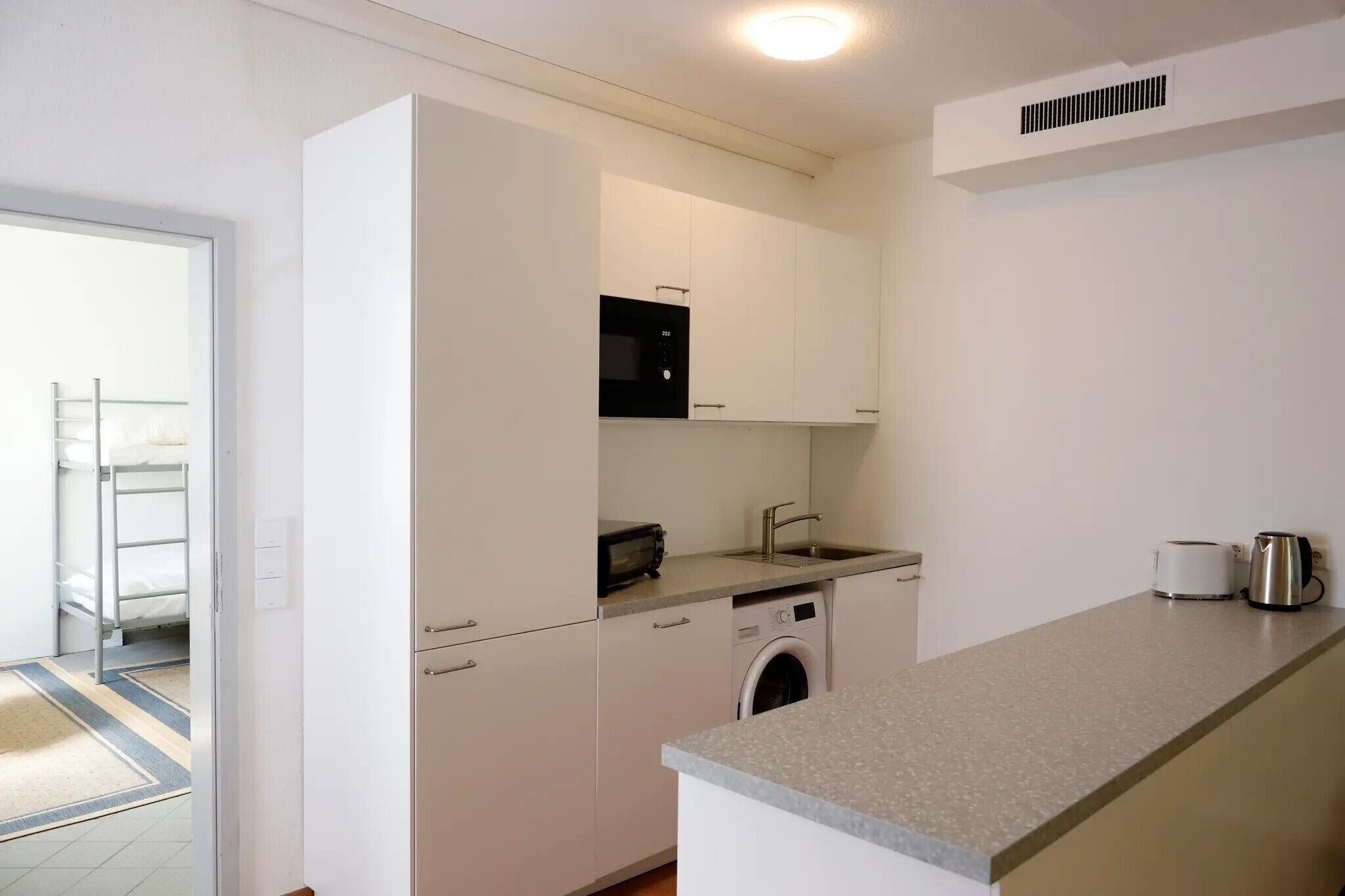 Cocina compacta con lavadora, microondas y tostadora.