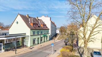 Straßenansicht mit Gebäuden, einer Straße und einem Baum.