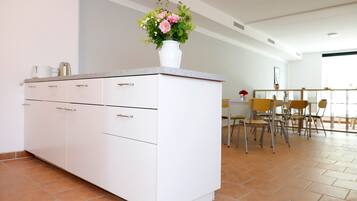 Una cuina moderna amb armaris blancs, taulell i un ram de flors.