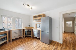 Een koelkast, een kookplaat, een waterkoker, kookgerei, borden en bestek