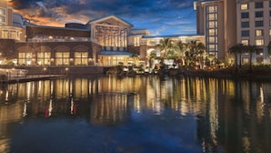 A hotel with a large pool, reflecting buildings, and palm trees.