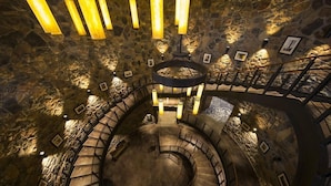 A spiral staircase in a stone-walled interior with multiple levels and railings.