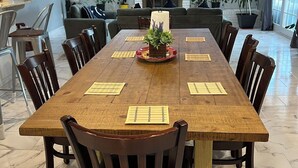 A dining area with a long wooden table, multiple chairs, a central plant, and a ceiling fan. - Cozy 4BR Home with Office, Fitness Area, Spacious Backyard & Pet-Friendl (Monroe)