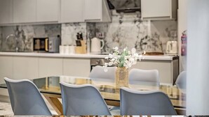 A modern kitchen with white cabinets, a marble backsplash, and a dining area with a glass table and chairs. - 4 Br & 4 Bath Cowley House Sleep 10 with Parking (Oxford)