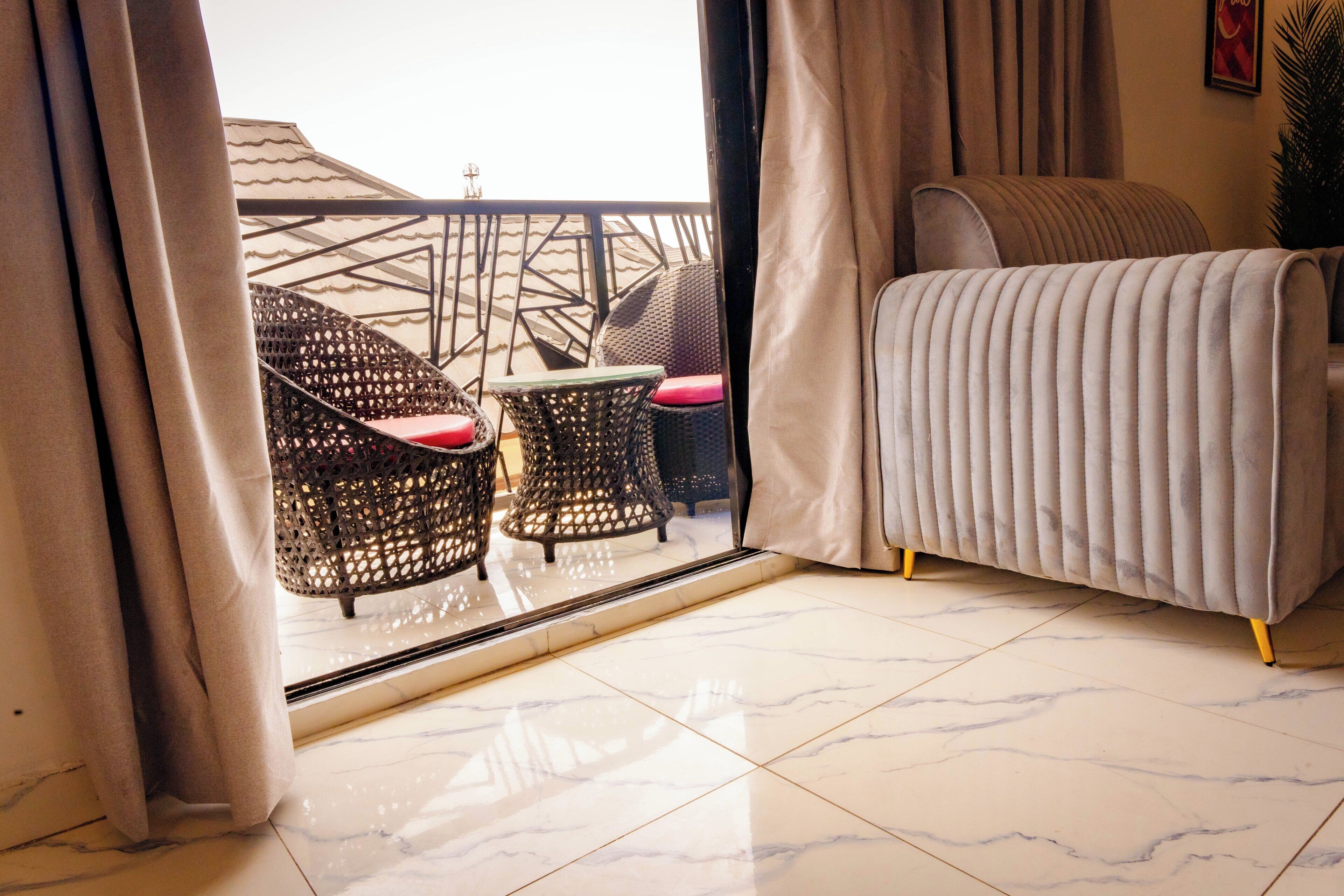 Ein Zimmer mit Balkon, einer Couch und Korbsesseln.