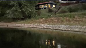 A house with a red roof, a visible staircase, and a body of water in the foreground. - Hot tub, boat dock and lakeside with this snug cabin. TINY BEDROOMS (Eucha)