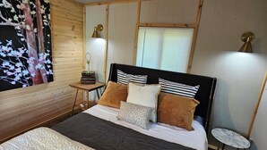 Un dormitorio con una cama grande, una mesita pequeña, una lámpara y un estante en la pared.