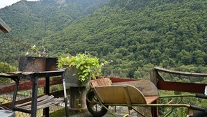 Un espacio al aire libre rústico con un carretón, una jardinera de metal con plantas y un banco de madera.