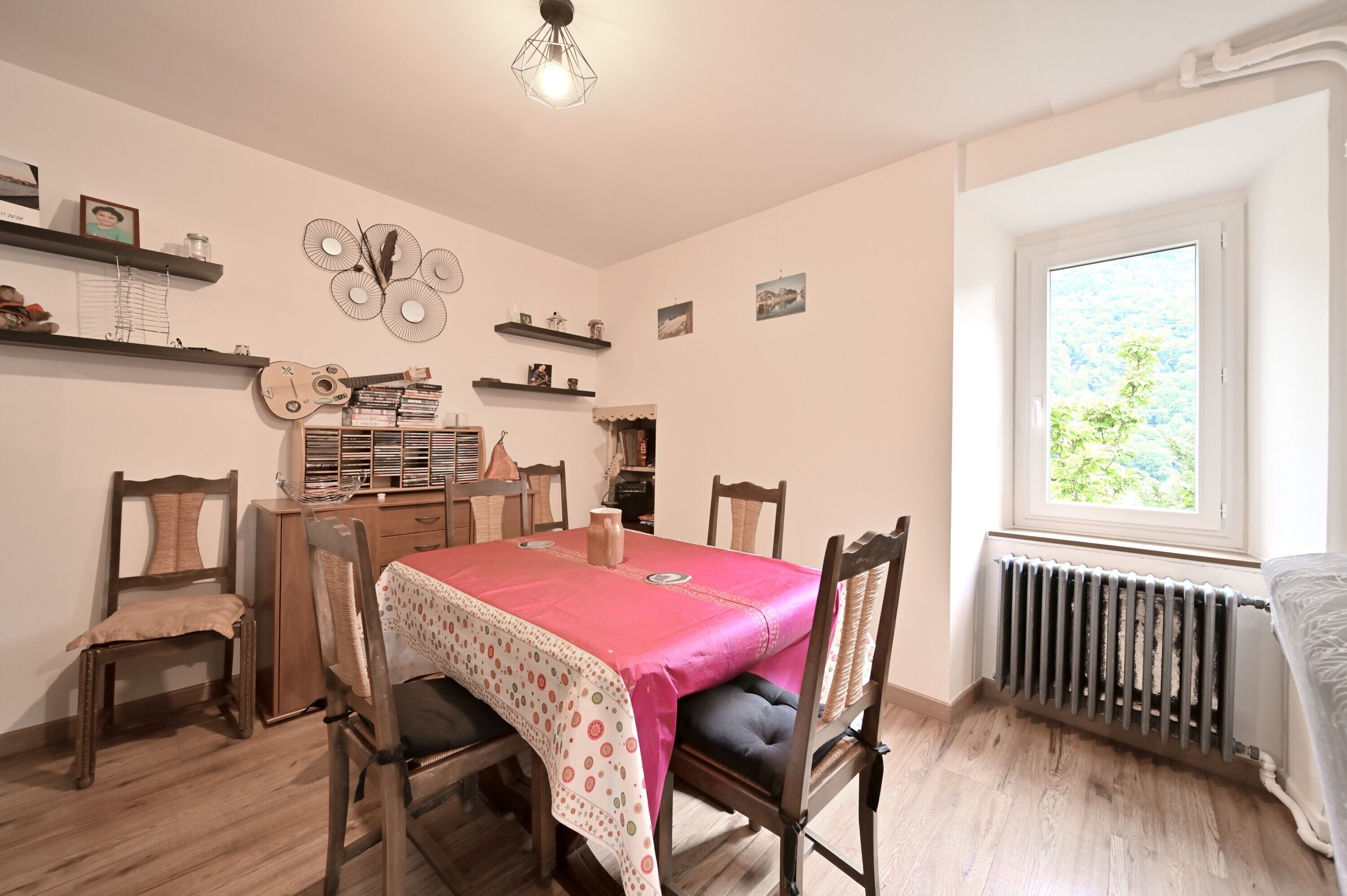 Un coin repas avec une table dressée pour quatre personnes, entourée de chaises en bois dotées d’assises rembourrées.