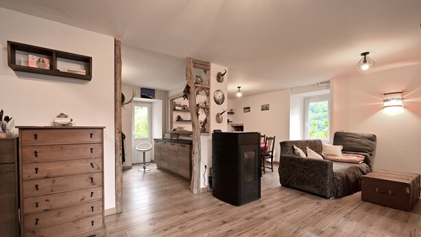 Amplia sala de estar con piso de madera, un mueble negro, un sofá y una maleta.