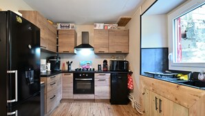 Una cocina compacta con un refrigerador negro, armarios de madera, un microondas y una ventana con vistas al exterior.