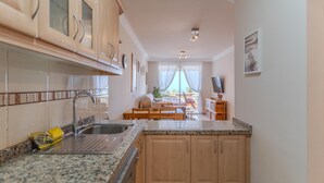 A modern kitchen with granite countertops, wooden cabinets, and a built-in dishwasher. - Sunset, Apartment in Costa Adeje - Relax in Paradise (Costa Adeje)