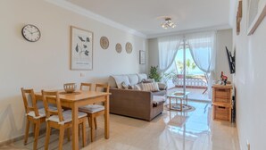 A spacious living area with a dining table, chairs, a sofa, and a balcony with a view. - Sunset, Apartment in Costa Adeje - Relax in Paradise (Costa Adeje)