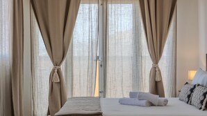 A hotel room with a bed, curtains, and a view through a window.