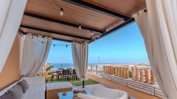 A balcony with wicker furniture, a table, and curtains.