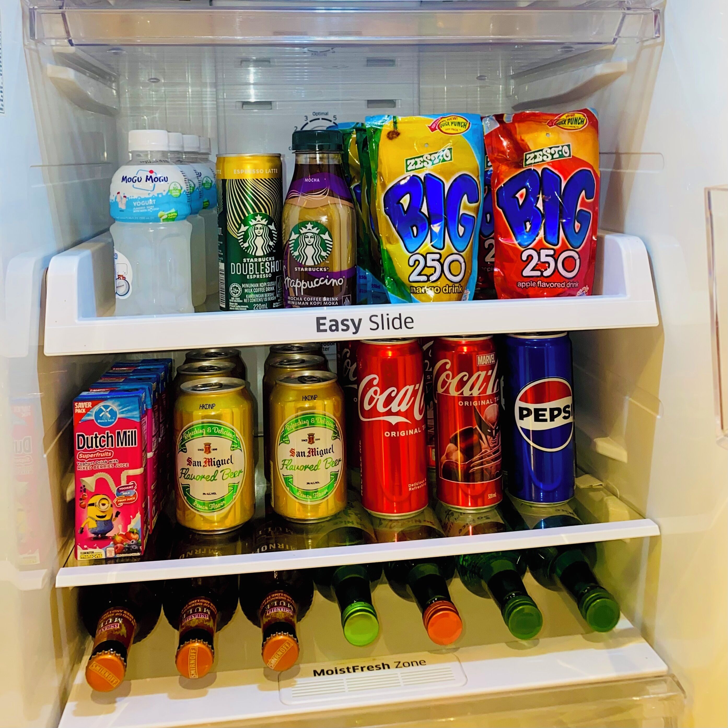 Un refrigerador lleno de diversas bebidas, incluyendo Starbucks, Big 250 y Coca-Cola.