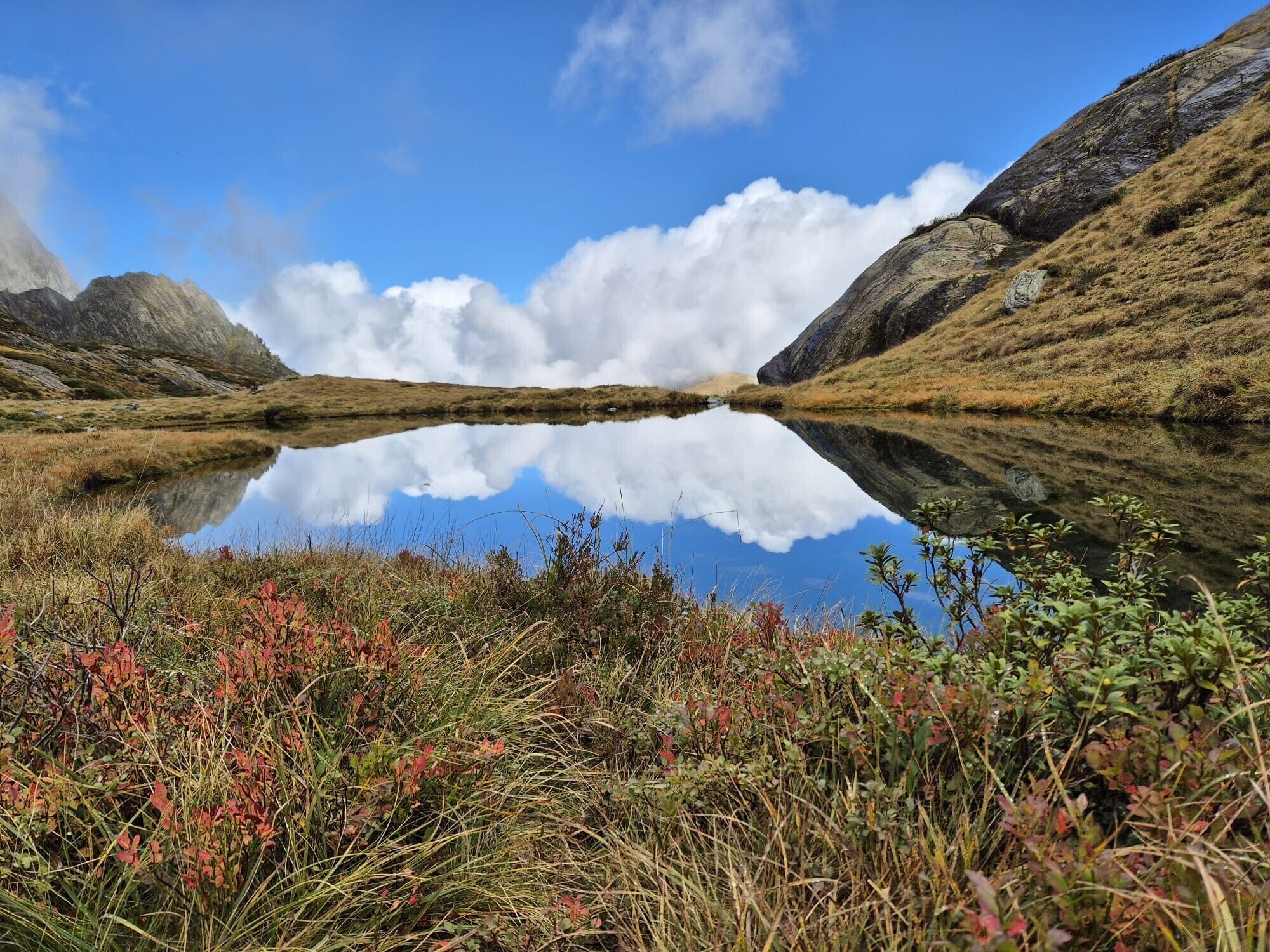 A natural landscape with a lake reflecting the sky and surrounding hills.