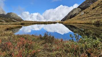 A natural landscape with a lake reflecting the sky and surrounding hills.