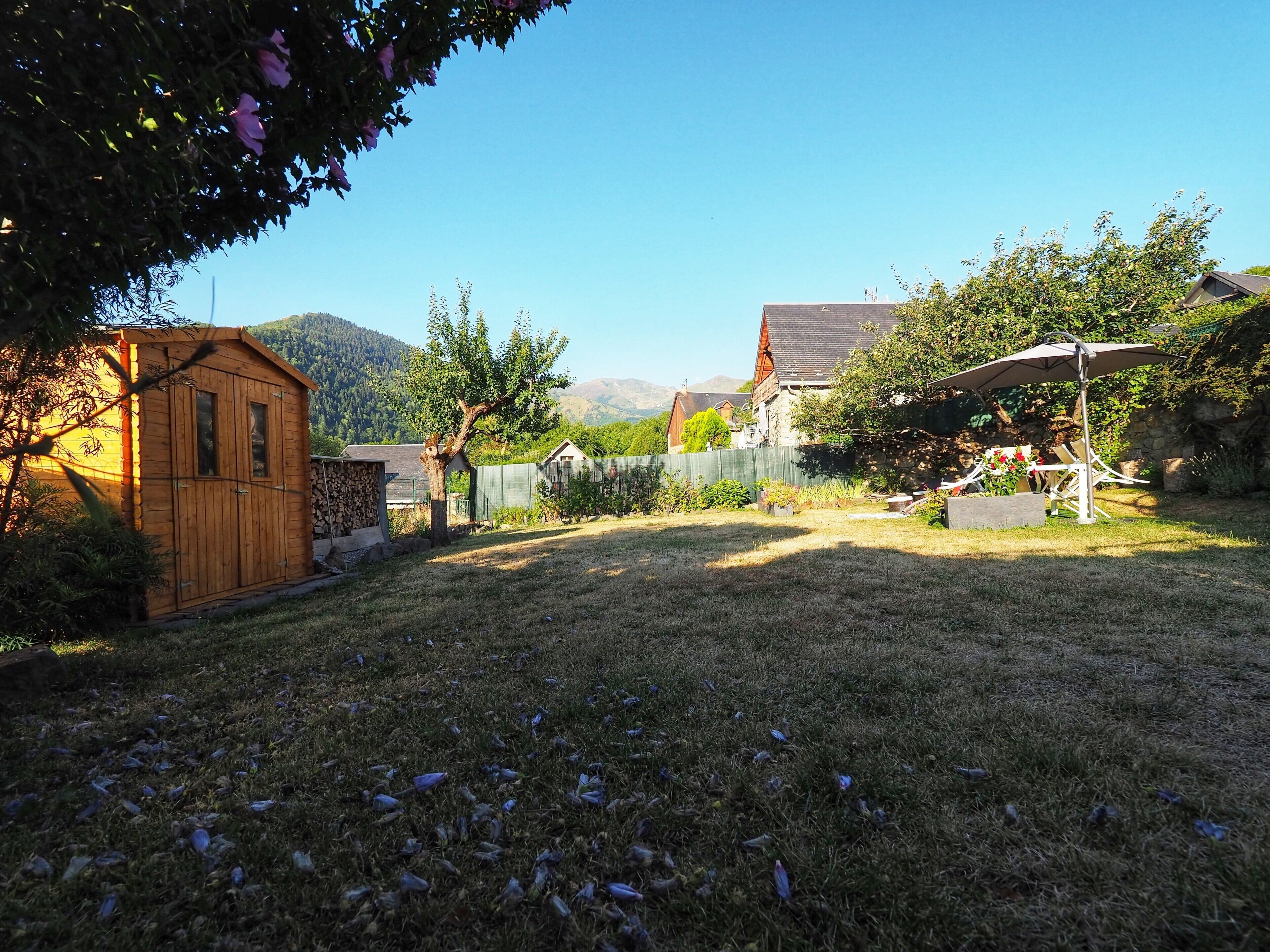 A backyard with a wooden shed, a fenced area, and a patio with outdoor furniture.