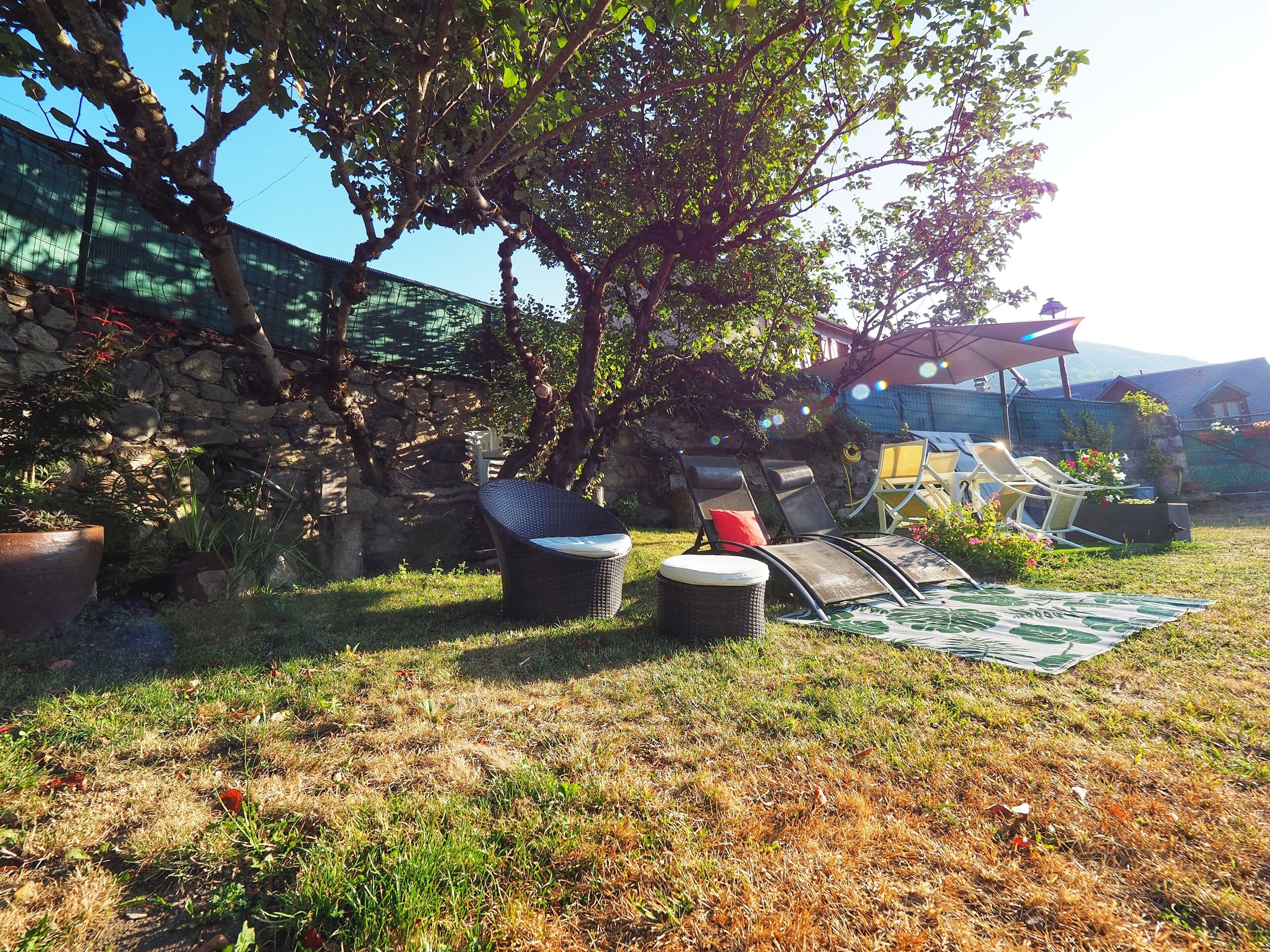 A garden area with outdoor seating, a stone wall, and a pergola.