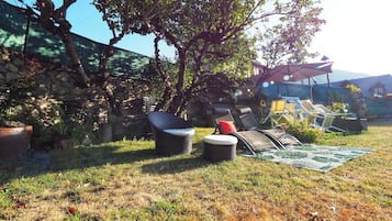 A garden area with outdoor seating, a stone wall, and a pergola.