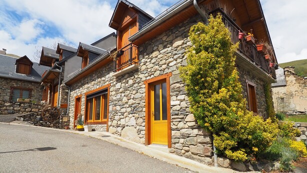 A stone building with wooden balconies and a clear sky. - Apartment 'La Grange' with Mountain View, Private Garden and Wi-Fi (Cazeaux-de-Larboust)