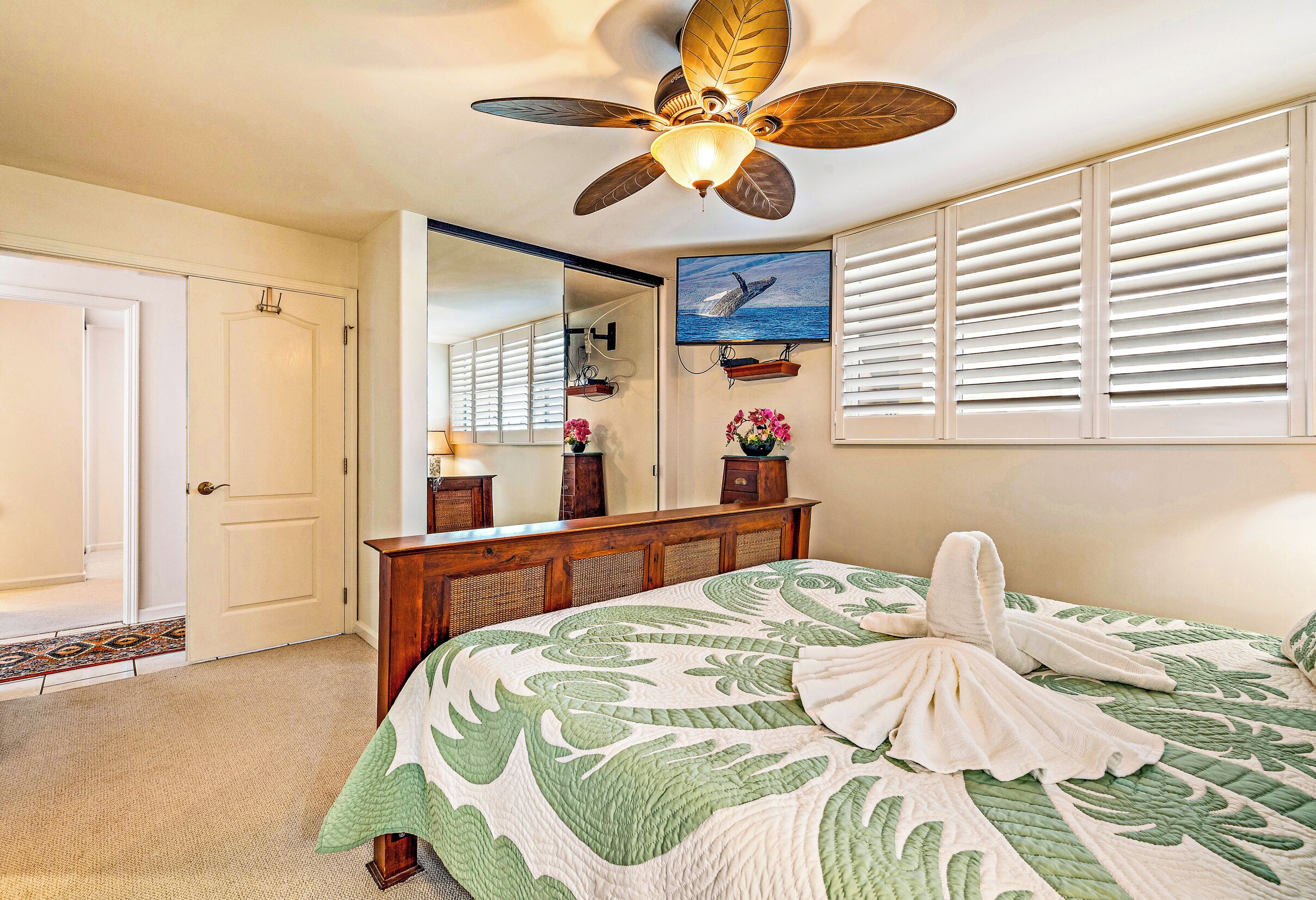 A bedroom with a bed, a ceiling fan, a dresser, a mirror, and a window with blinds.