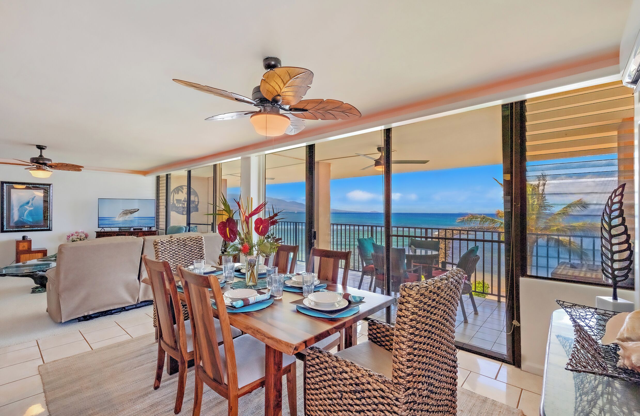 Un comedor con mesa preparada para cuatro personas, ventanas amplias y vista al océano.