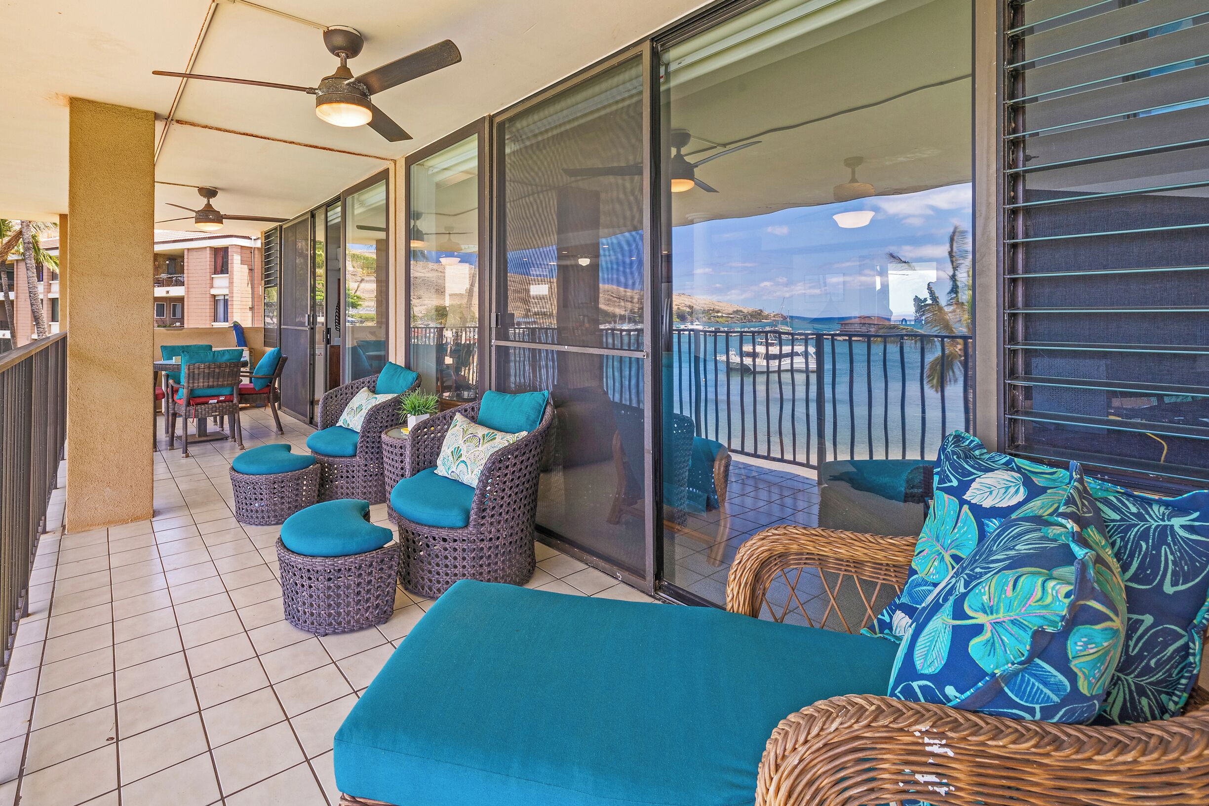 A balcony with wicker furniture, a glass door, and a view of the sea.