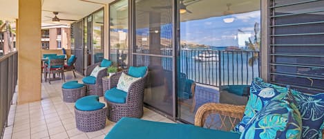 A balcony with wicker furniture, a glass door, and a view of the sea.