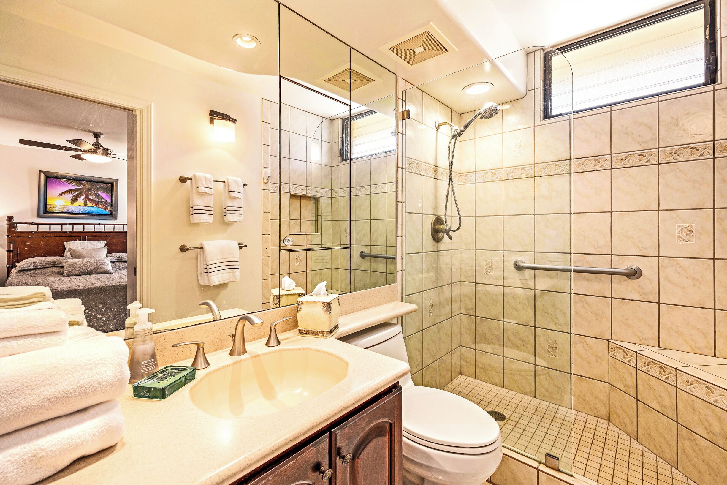 A modern bathroom with a glass-enclosed shower, a sink with toiletries, and a toilet.