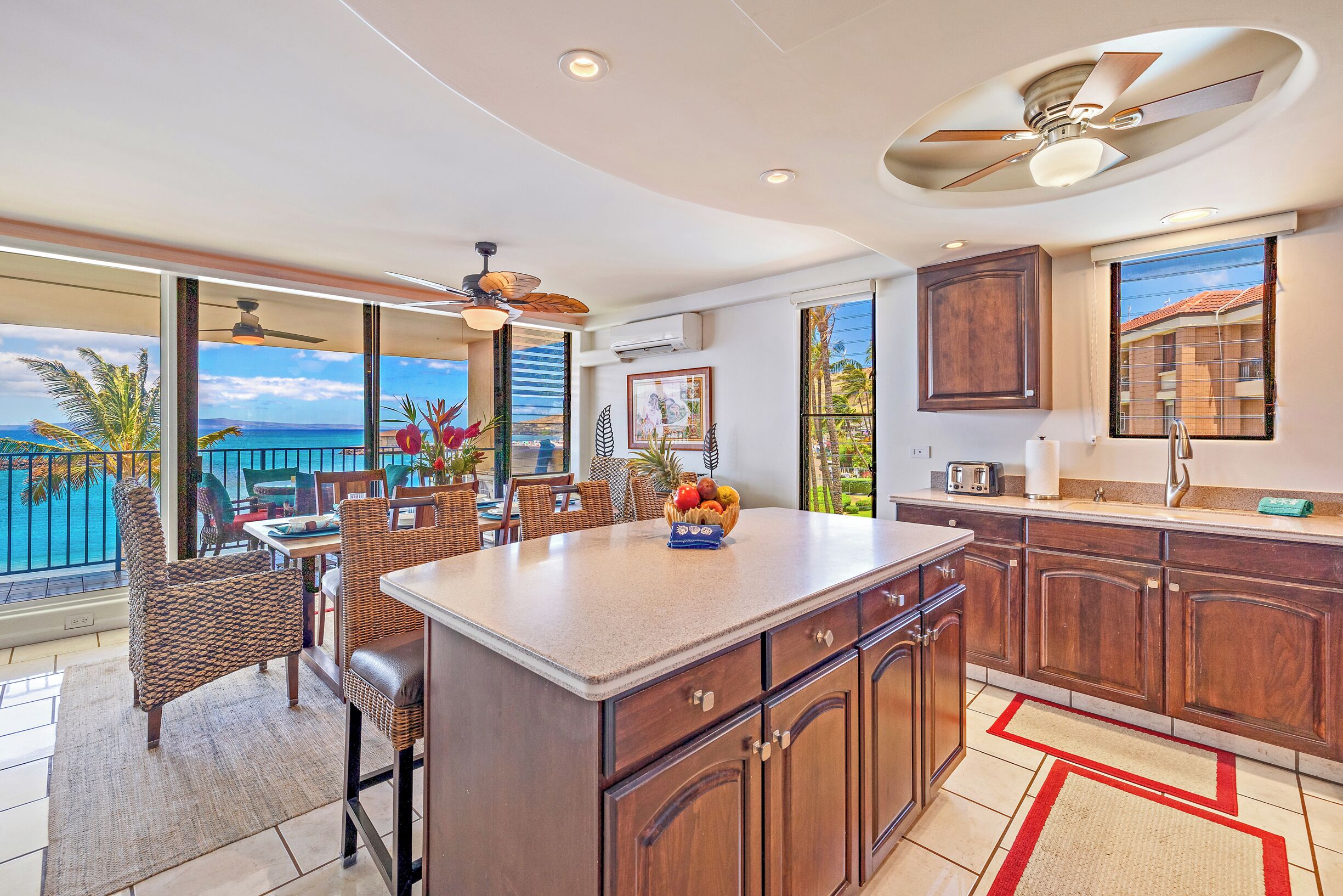 A kitchen with a large island, wooden cabinets, and a view of the ocean.
